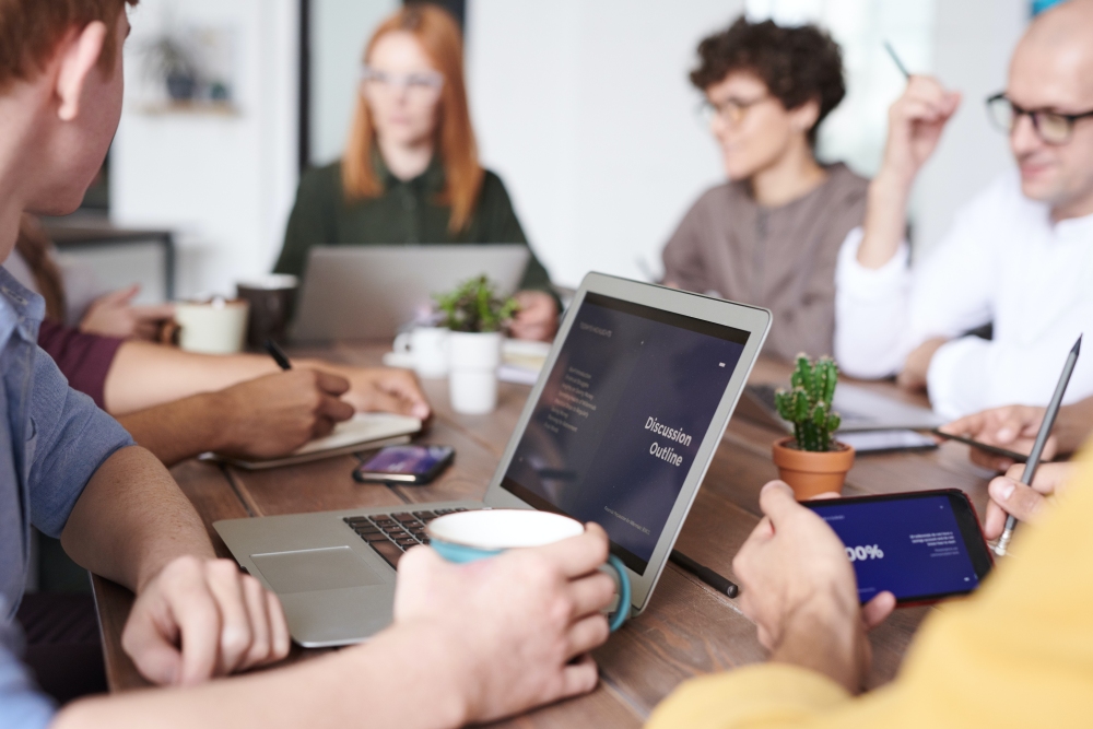 people in meeting with focus on laptop